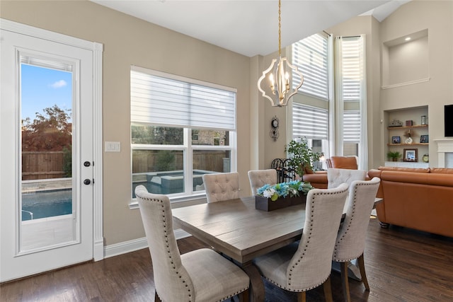 dining area with vaulted ceiling, dark hardwood / wood-style flooring, built in features, and a chandelier