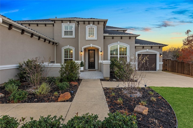 mediterranean / spanish-style home with fence, stucco siding, concrete driveway, and an attached garage