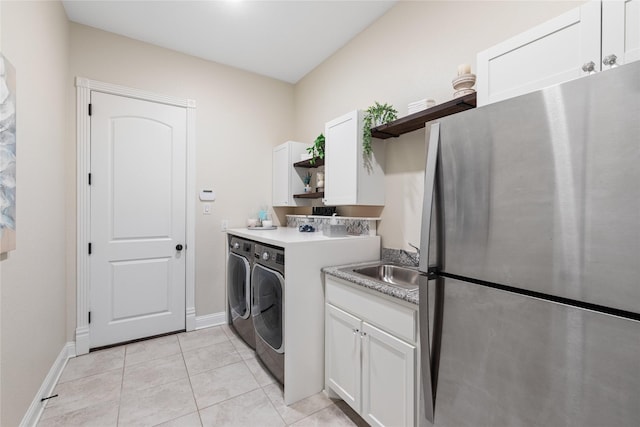 washroom featuring independent washer and dryer, light tile patterned floors, cabinet space, a sink, and baseboards