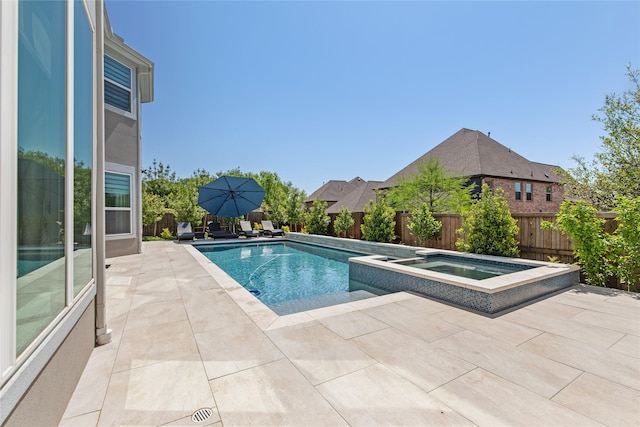 view of pool featuring a pool with connected hot tub, a patio, and a fenced backyard