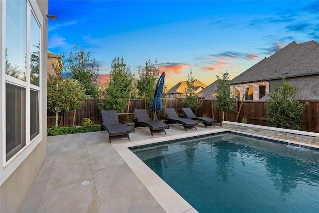 pool at dusk with pool water feature and a patio