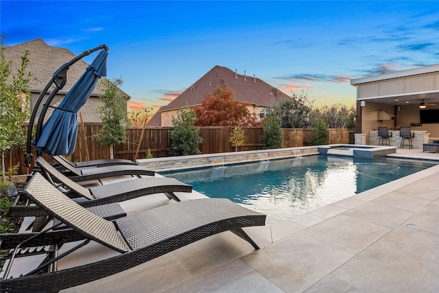 pool at dusk with an in ground hot tub, a bar, and a patio