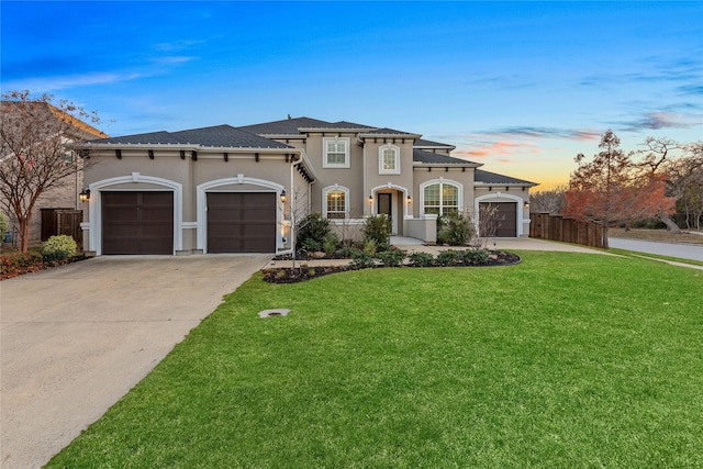 mediterranean / spanish house featuring a garage, a lawn, concrete driveway, stucco siding, and fence
