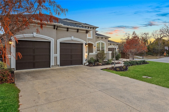 mediterranean / spanish home with driveway, an attached garage, stucco siding, and a front lawn