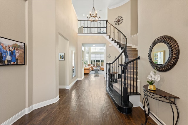 entryway featuring a towering ceiling, dark hardwood / wood-style floors, and an inviting chandelier