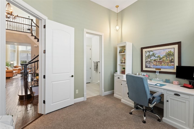 carpeted home office featuring a high ceiling and a chandelier