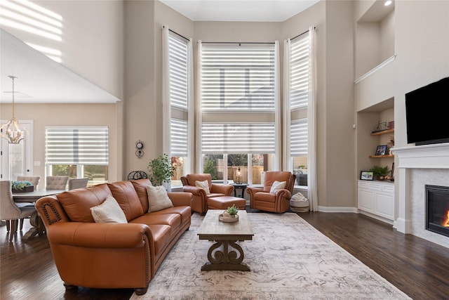 living room featuring an inviting chandelier, built in features, plenty of natural light, and dark wood-type flooring