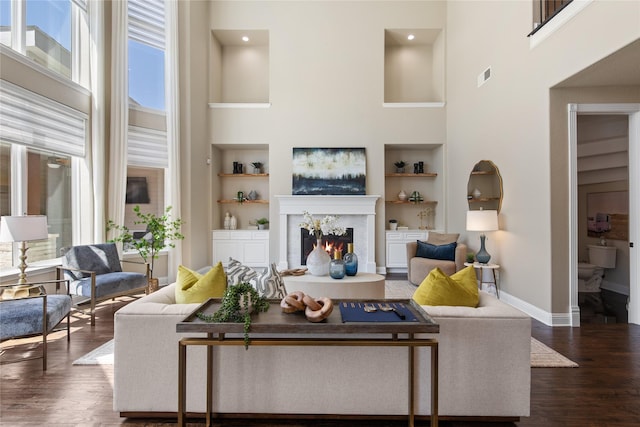 living area featuring a wealth of natural light, visible vents, a high ceiling, and built in shelves