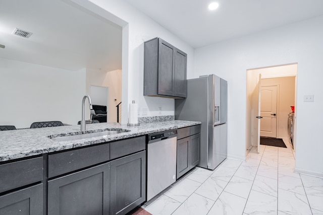 kitchen with light stone counters, sink, and appliances with stainless steel finishes