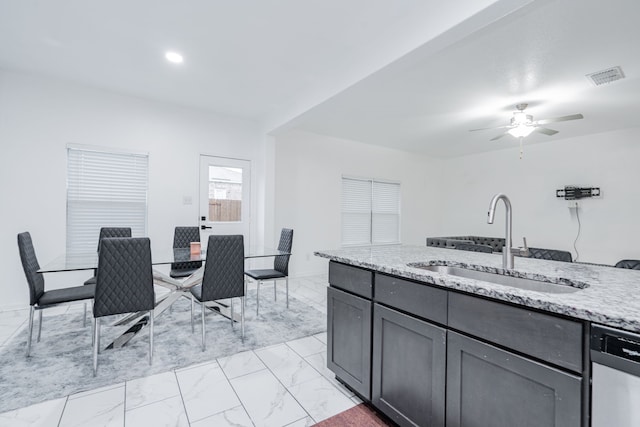 kitchen with dishwasher, ceiling fan, light stone countertops, and sink