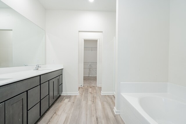 bathroom featuring a tub to relax in, vanity, and wood-type flooring