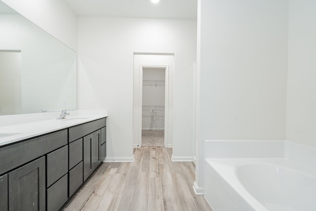 bathroom featuring hardwood / wood-style flooring, vanity, and a tub to relax in