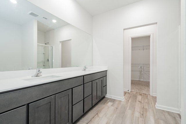 bathroom with hardwood / wood-style floors, vanity, and a shower with shower door