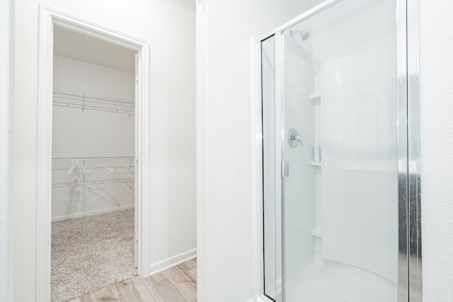 bathroom with hardwood / wood-style flooring and a shower with shower door