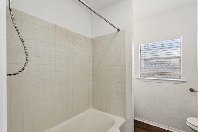 bathroom with toilet, hardwood / wood-style floors, and tiled shower / bath