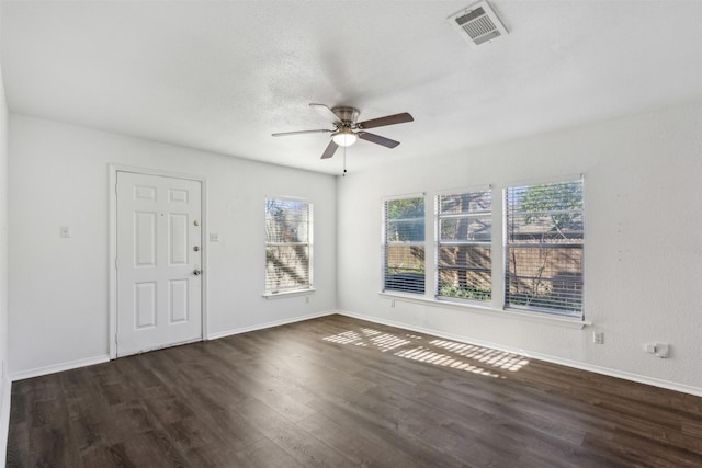 spare room featuring ceiling fan, plenty of natural light, and dark wood-type flooring