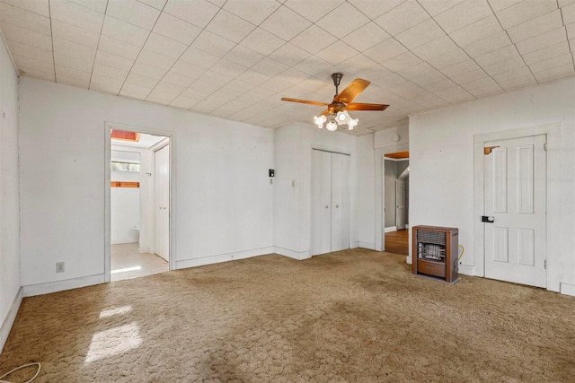 unfurnished bedroom featuring heating unit, ensuite bath, ceiling fan, and light colored carpet