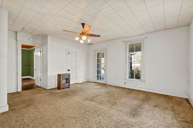 spare room with heating unit, ceiling fan, and carpet