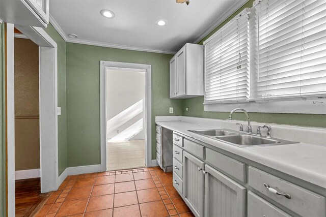 kitchen with white cabinets, light tile patterned floors, sink, and ornamental molding