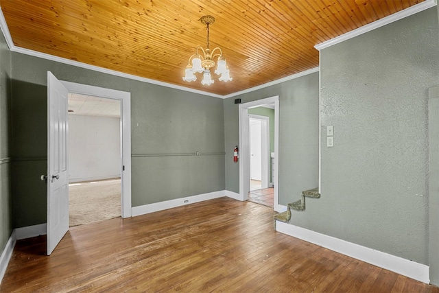 spare room with hardwood / wood-style floors, an inviting chandelier, wood ceiling, and ornamental molding