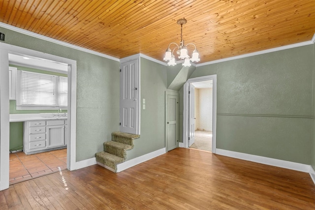 unfurnished dining area featuring light wood-type flooring, wood ceiling, crown molding, sink, and an inviting chandelier