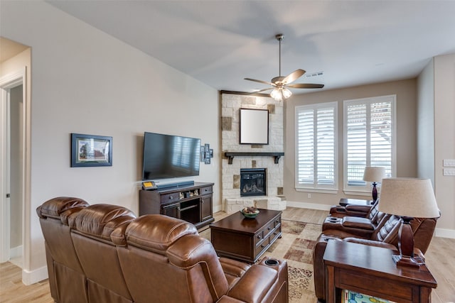 living room featuring ceiling fan, a fireplace, and light hardwood / wood-style flooring