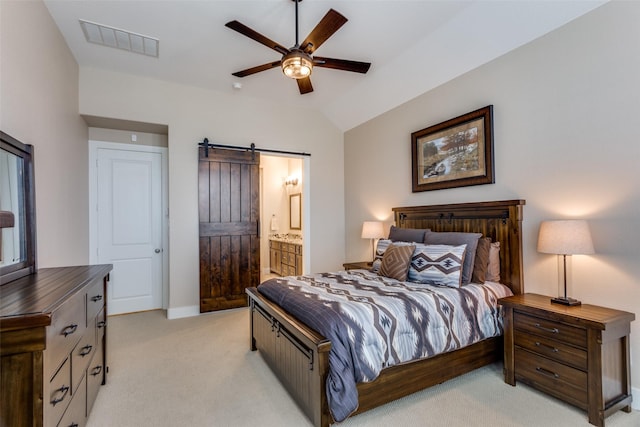 bedroom with connected bathroom, vaulted ceiling, light carpet, ceiling fan, and a barn door