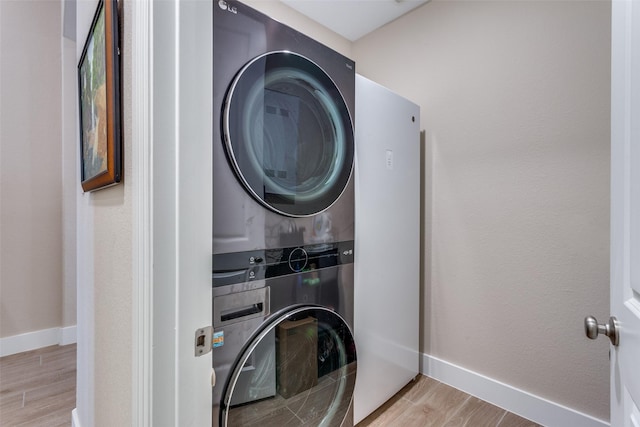 laundry room featuring stacked washer and dryer and light hardwood / wood-style flooring