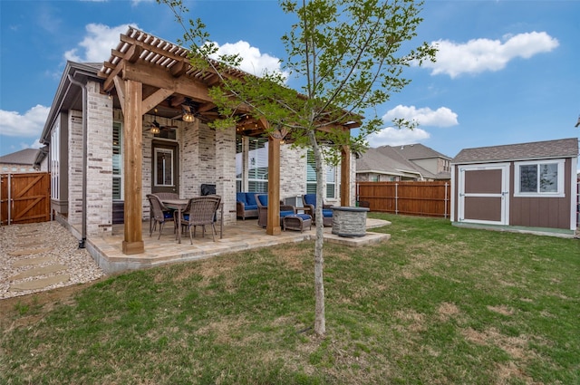 rear view of property with a patio area, a lawn, ceiling fan, a shed, and an outdoor living space with a fire pit