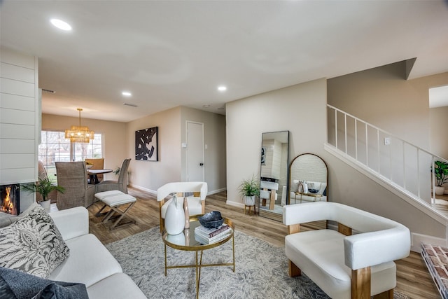 living room featuring a multi sided fireplace, a notable chandelier, and hardwood / wood-style flooring