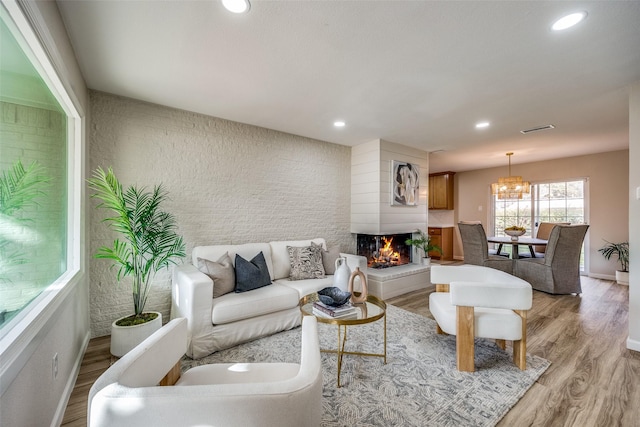 living room with a chandelier, a large fireplace, and light hardwood / wood-style floors