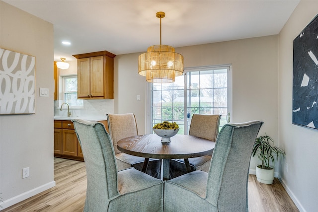 dining room with light wood-type flooring, an inviting chandelier, and sink