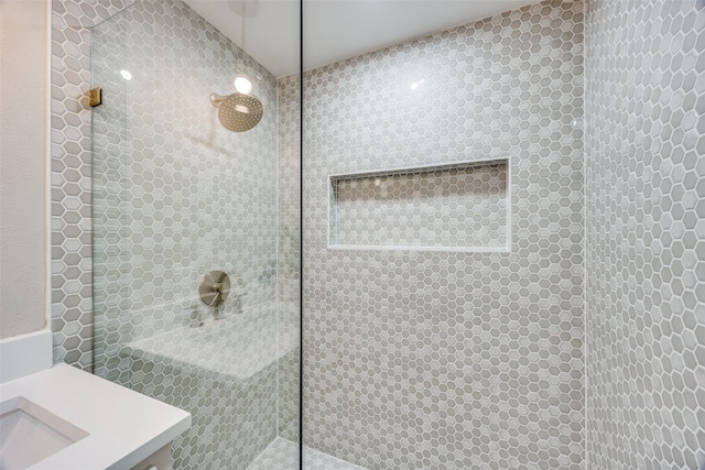 bathroom featuring tiled shower and sink