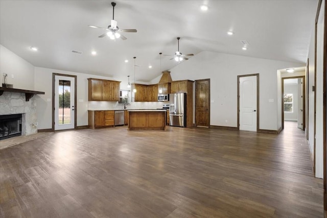 unfurnished living room with ceiling fan, high vaulted ceiling, a stone fireplace, dark wood-type flooring, and baseboards