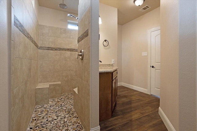 bathroom with a tile shower, vanity, and hardwood / wood-style flooring