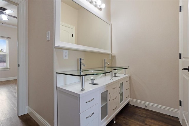 bathroom featuring vanity, baseboards, wood finished floors, and ornamental molding