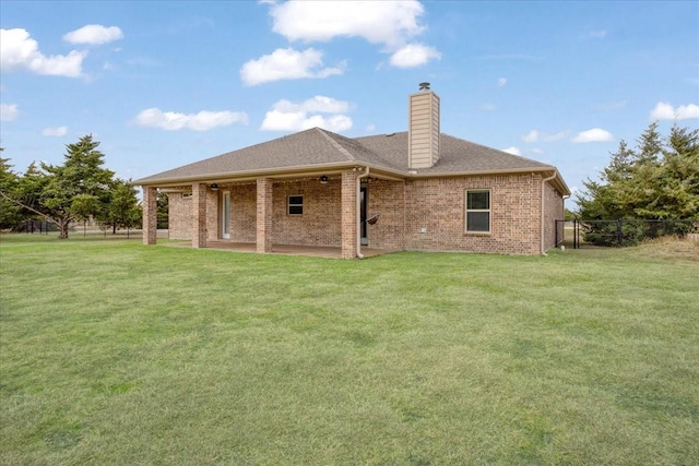 back of house with brick siding, a lawn, and fence