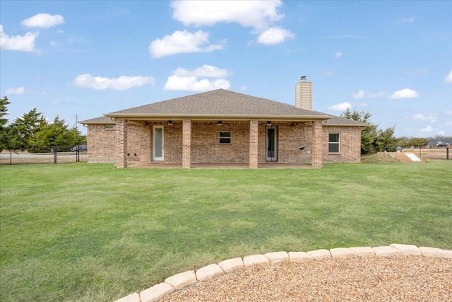 back of house with brick siding, ceiling fan, fence, and a yard