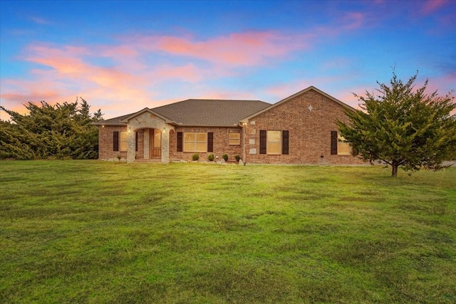 single story home with a yard and brick siding