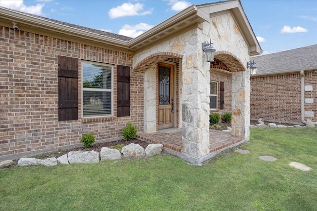 view of exterior entry with brick siding and a lawn