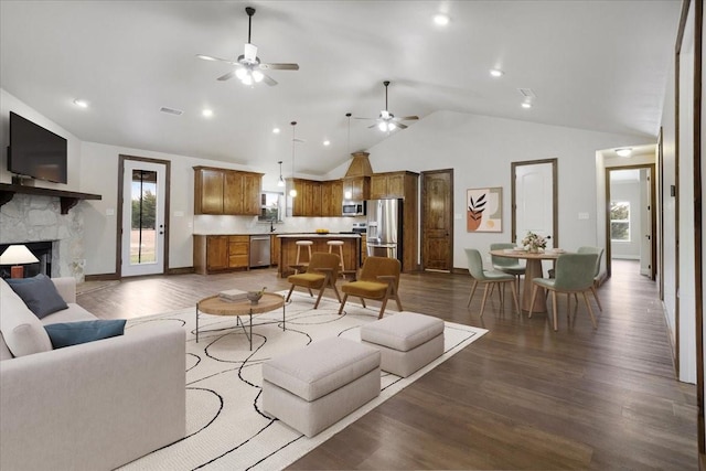 living room featuring ceiling fan, dark hardwood / wood-style flooring, a stone fireplace, and high vaulted ceiling