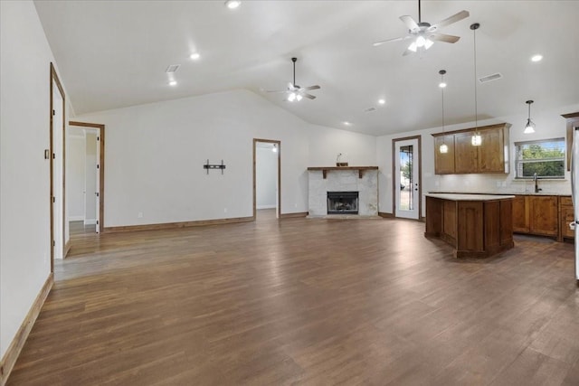 unfurnished living room with dark wood-type flooring, sink, vaulted ceiling, ceiling fan, and a fireplace