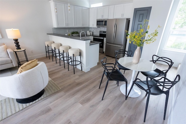 kitchen featuring appliances with stainless steel finishes, white cabinets, a kitchen breakfast bar, and kitchen peninsula