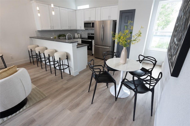 kitchen featuring a breakfast bar, white cabinetry, backsplash, kitchen peninsula, and stainless steel appliances