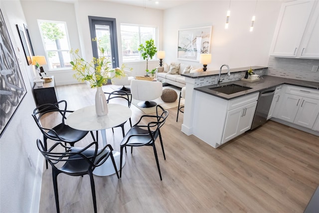 kitchen with a wealth of natural light, dishwasher, sink, white cabinets, and kitchen peninsula