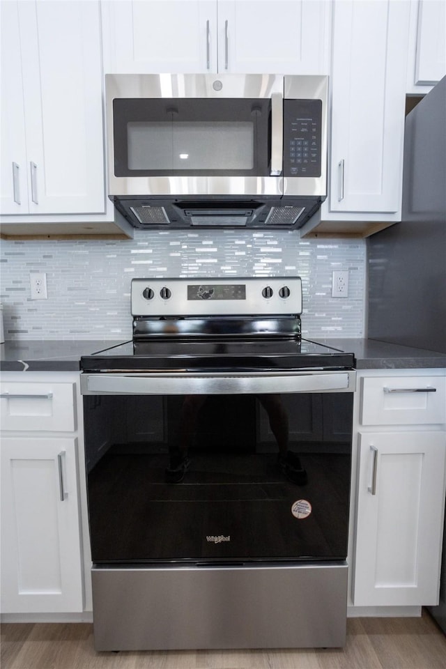 kitchen featuring stainless steel appliances, white cabinetry, and tasteful backsplash