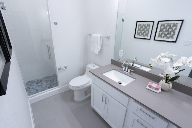 bathroom with a shower with door, vanity, tile patterned floors, and toilet