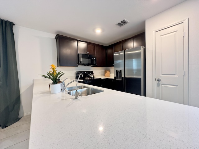 kitchen with sink, dark brown cabinetry, kitchen peninsula, and black appliances