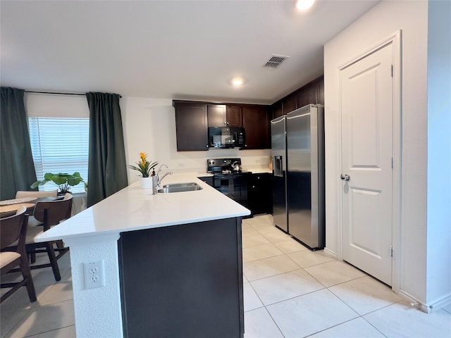 kitchen featuring black appliances, kitchen peninsula, sink, light tile patterned flooring, and dark brown cabinetry