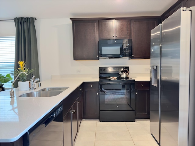 kitchen featuring dark brown cabinetry, sink, kitchen peninsula, light tile patterned floors, and black appliances